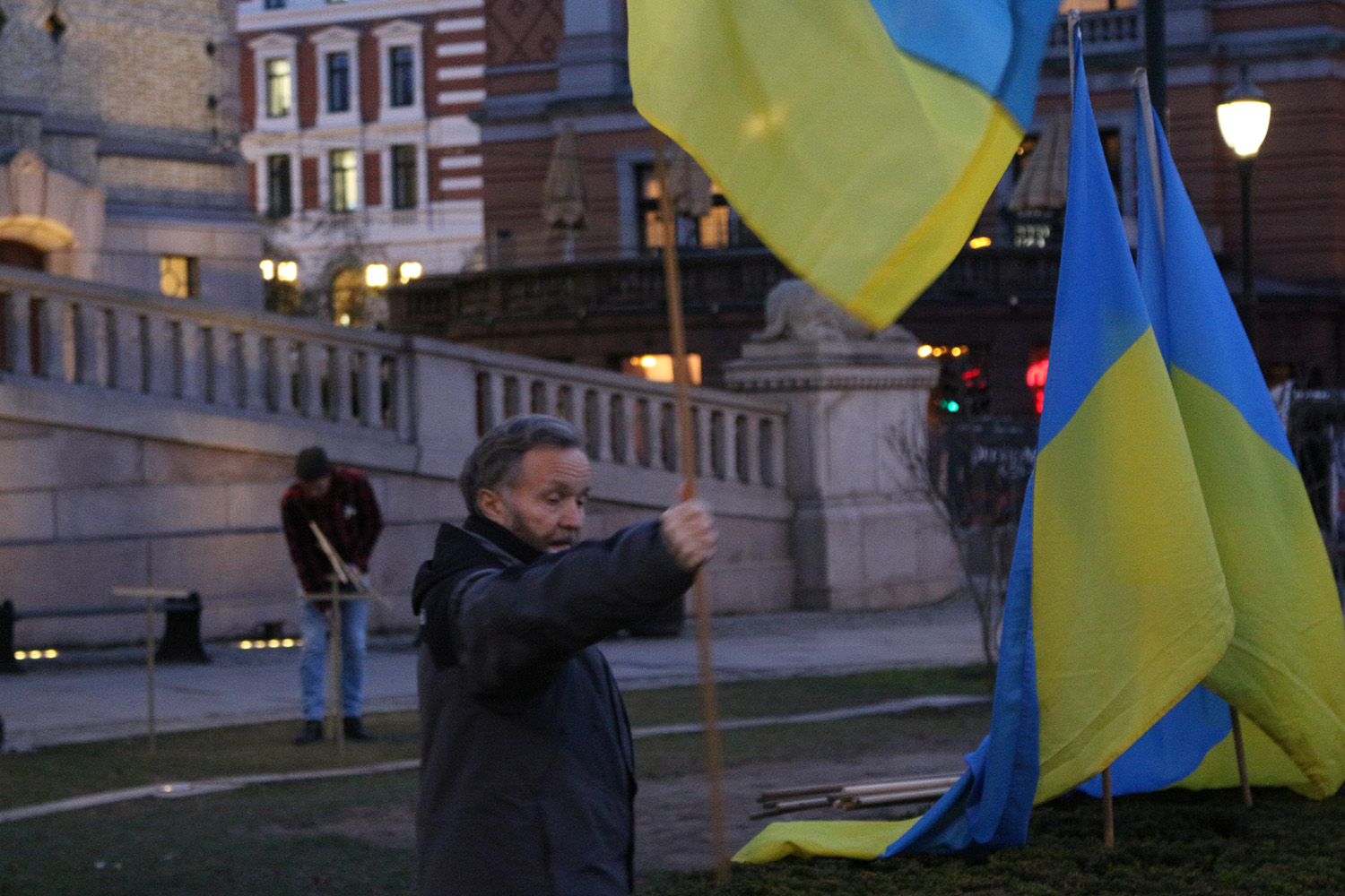 En mann planter et ukrainsk flagg i en busk