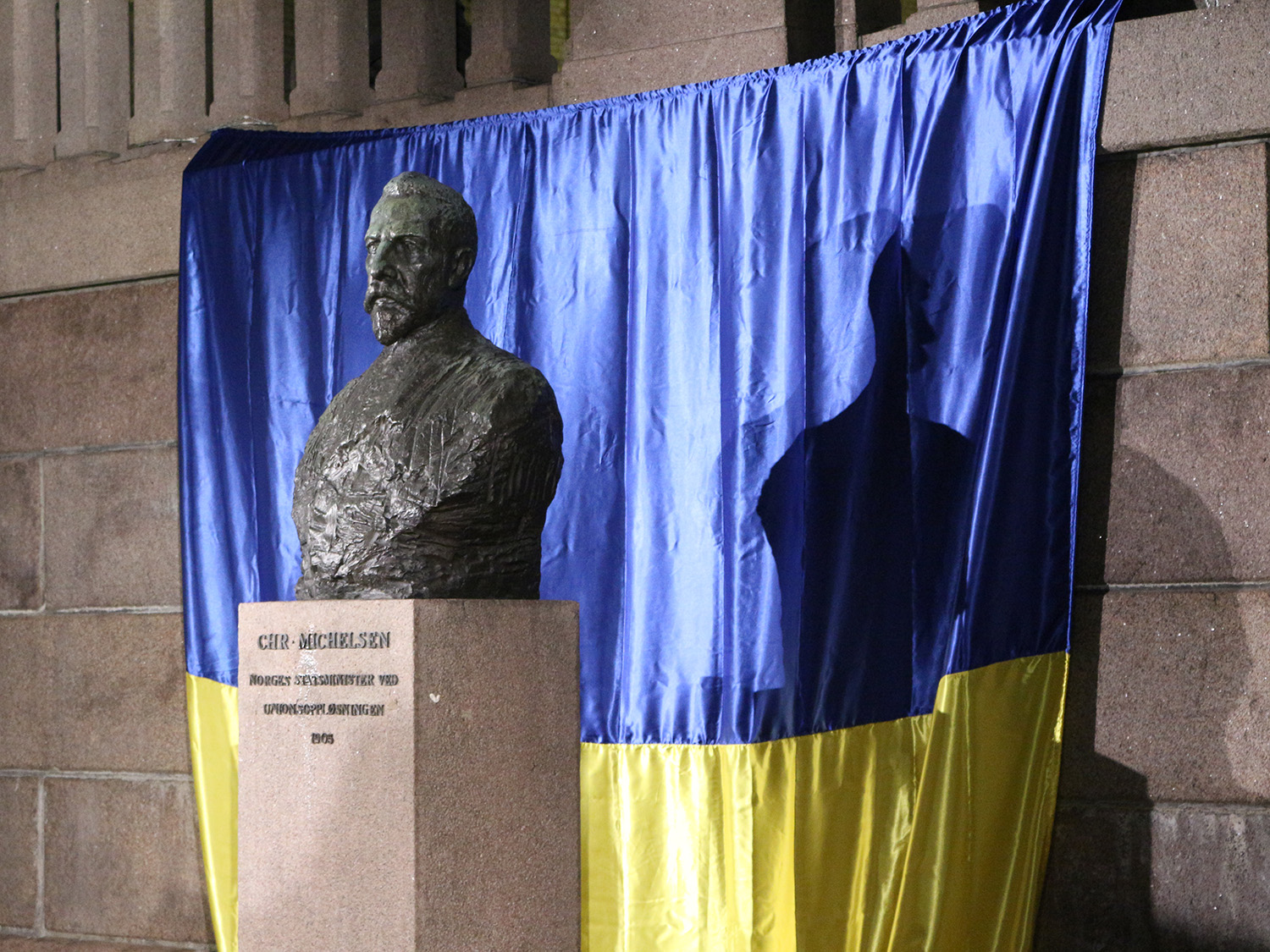 En statue av Christian Michelsen med det Ukrainske flagget hengende bak.