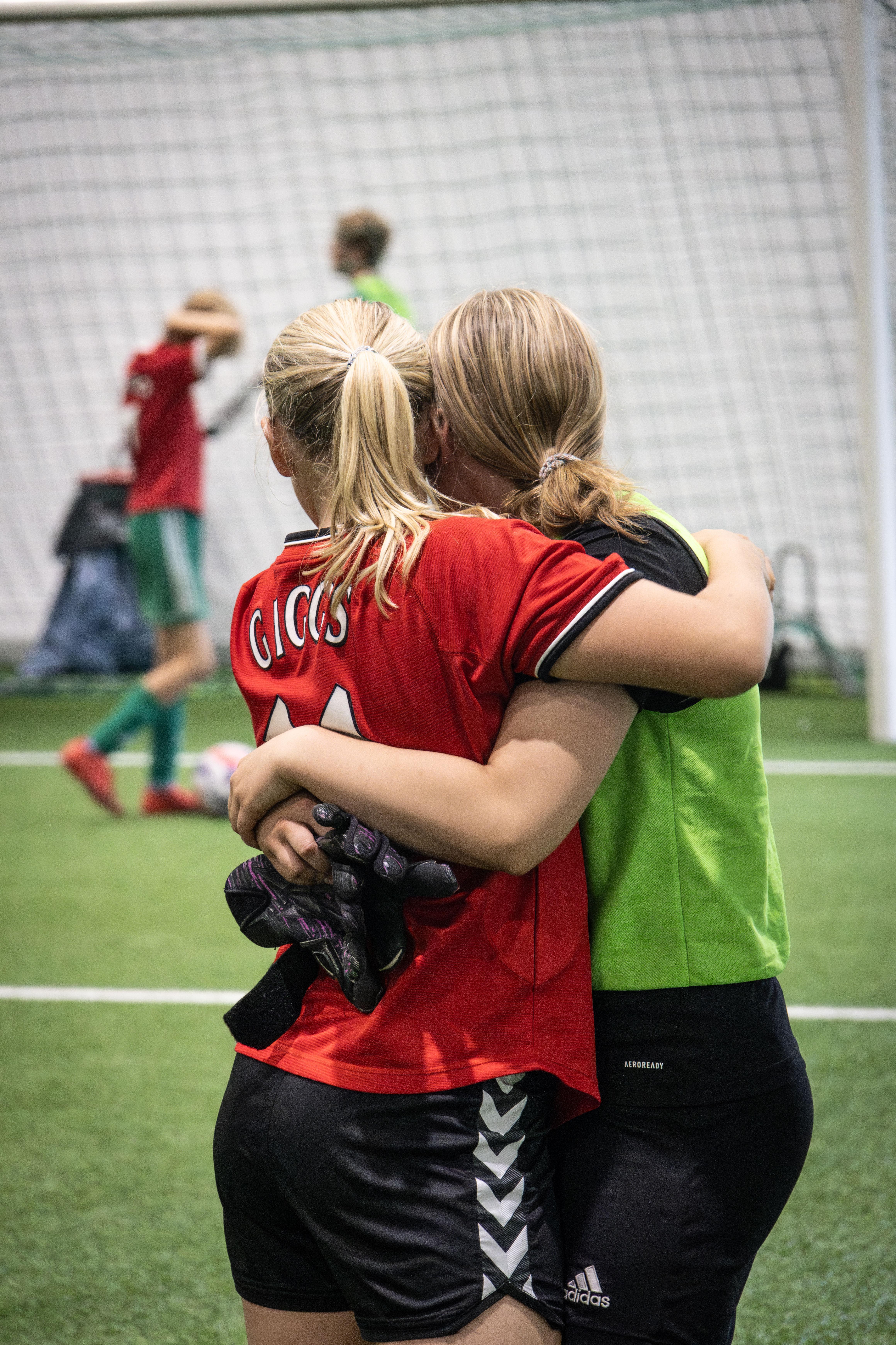 To jenter ikledd fotballtrøyer som klemmer