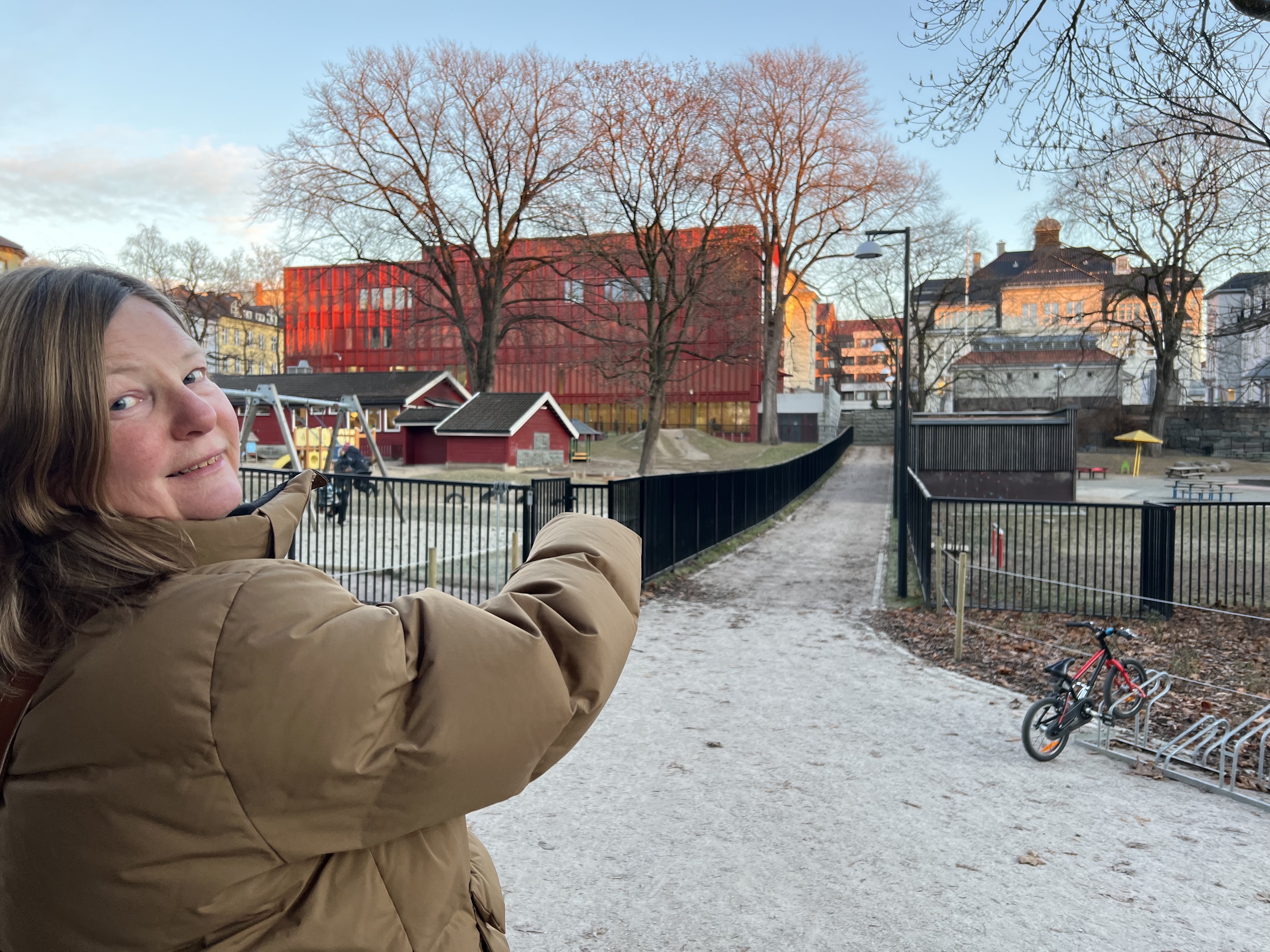 Dame som peker på veien mellom skolen og parken