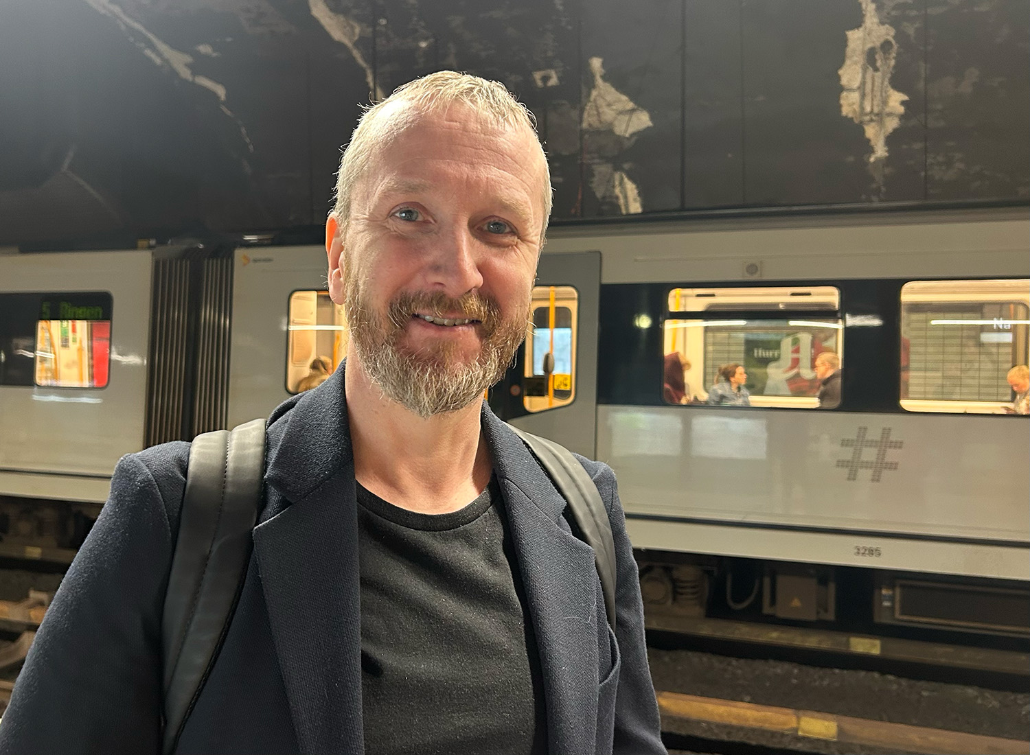 Mann som smiler på en t-banestasjon