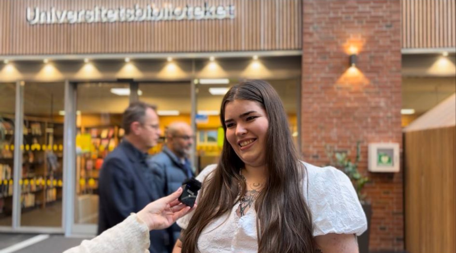 Bilde av student foran univeristetsbiblioteket