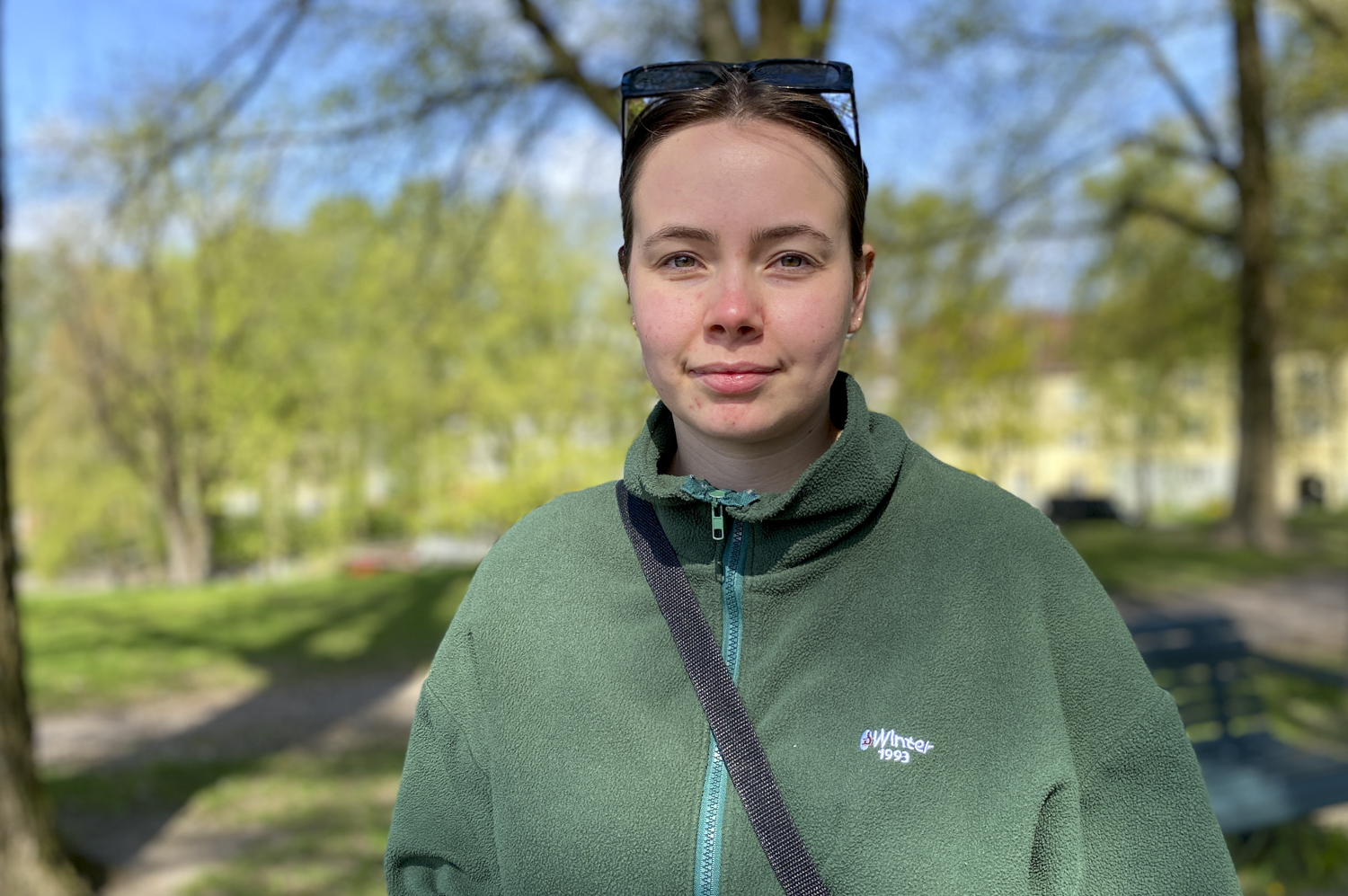 Mathea har på seg en grønn genser og smiler til kamera.