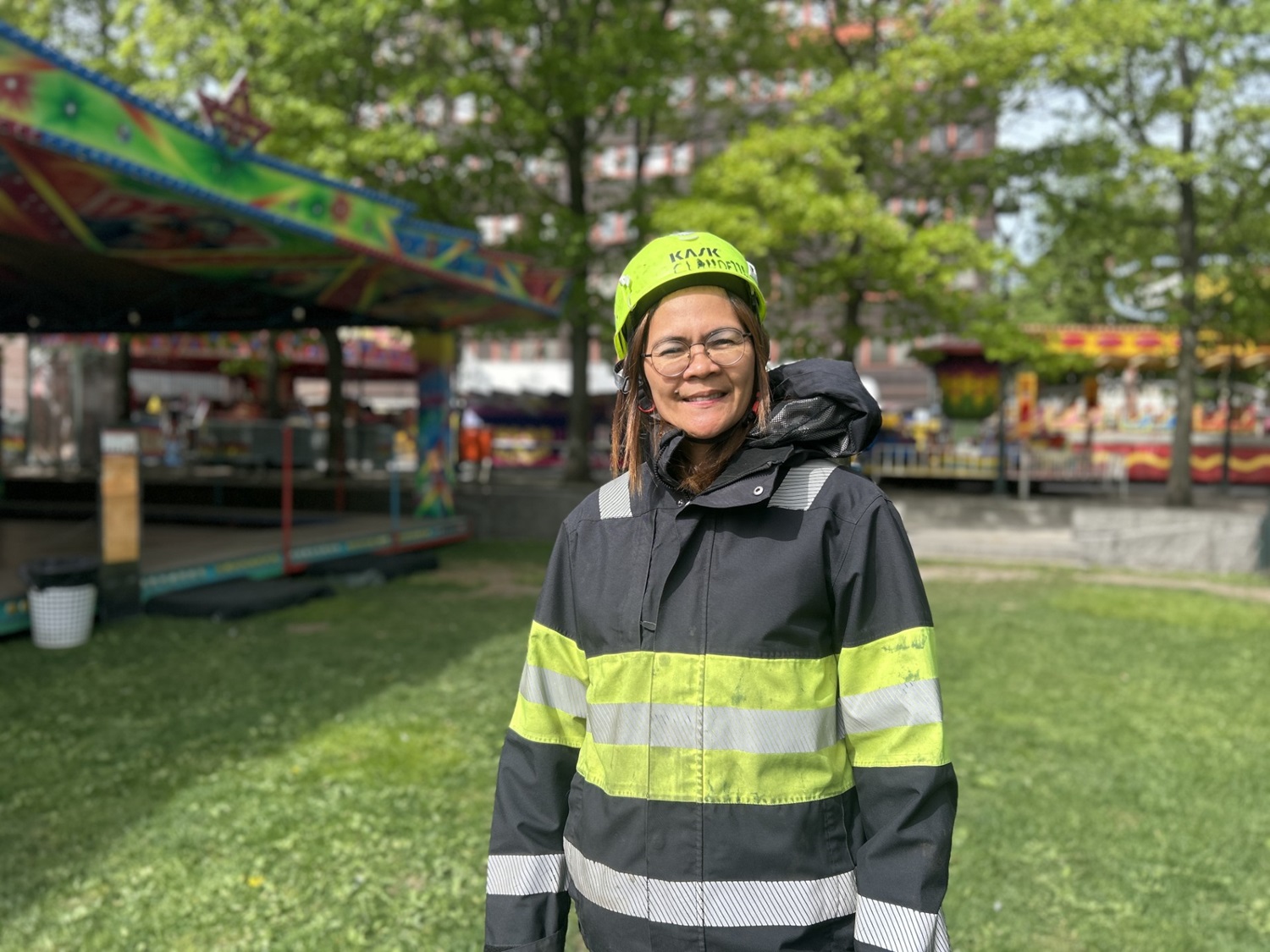 Dame med arbeidsjakke og hjelm på et tivoli