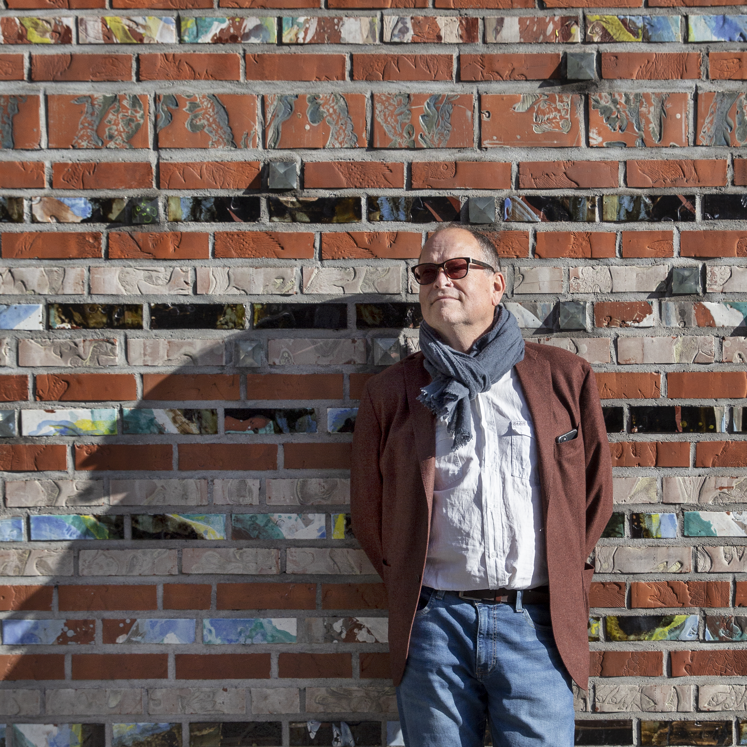 Lars Haukeland står inntil en murvegg