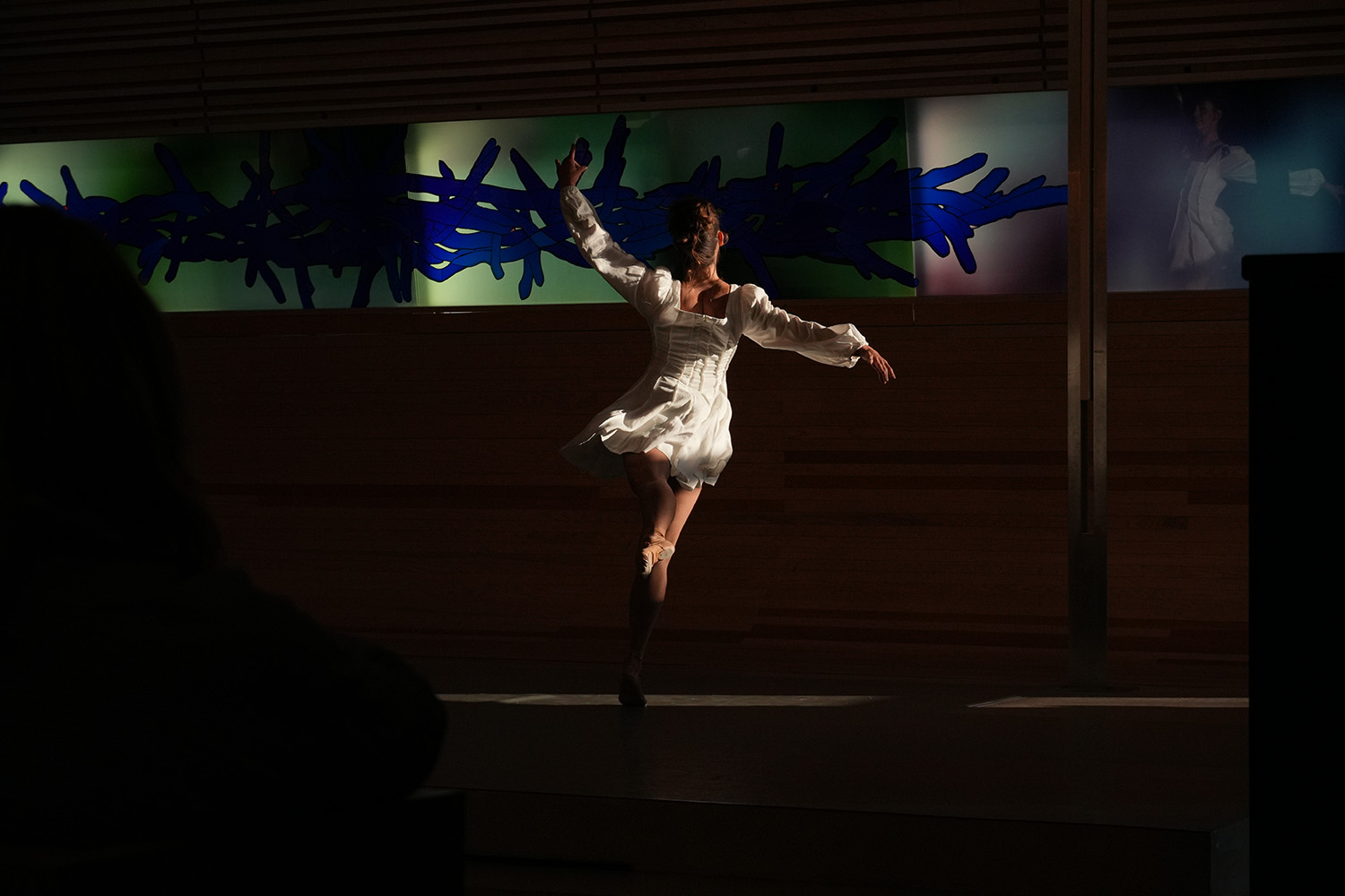En kvinne i hvit kjole danser elegant med ryggen vendt til kamera