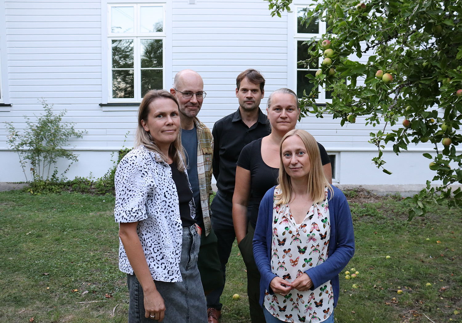 Fem foreldre ser bekymret mot kamera, de står i skolegården