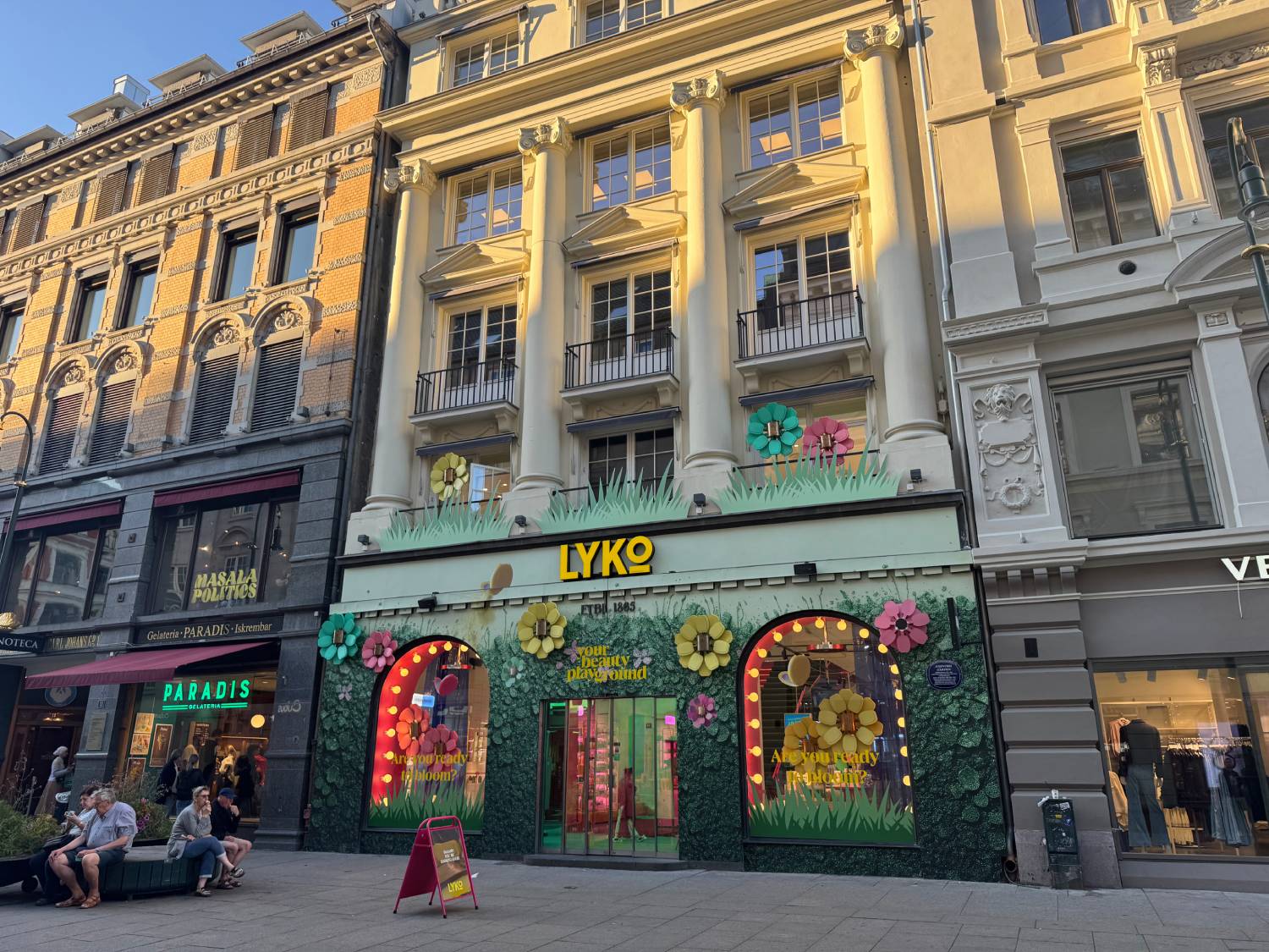 fargerik og stor fasade på butikk i Oslo. grønn bakgrunn med masse blomster og stort gult Lyko skilt.