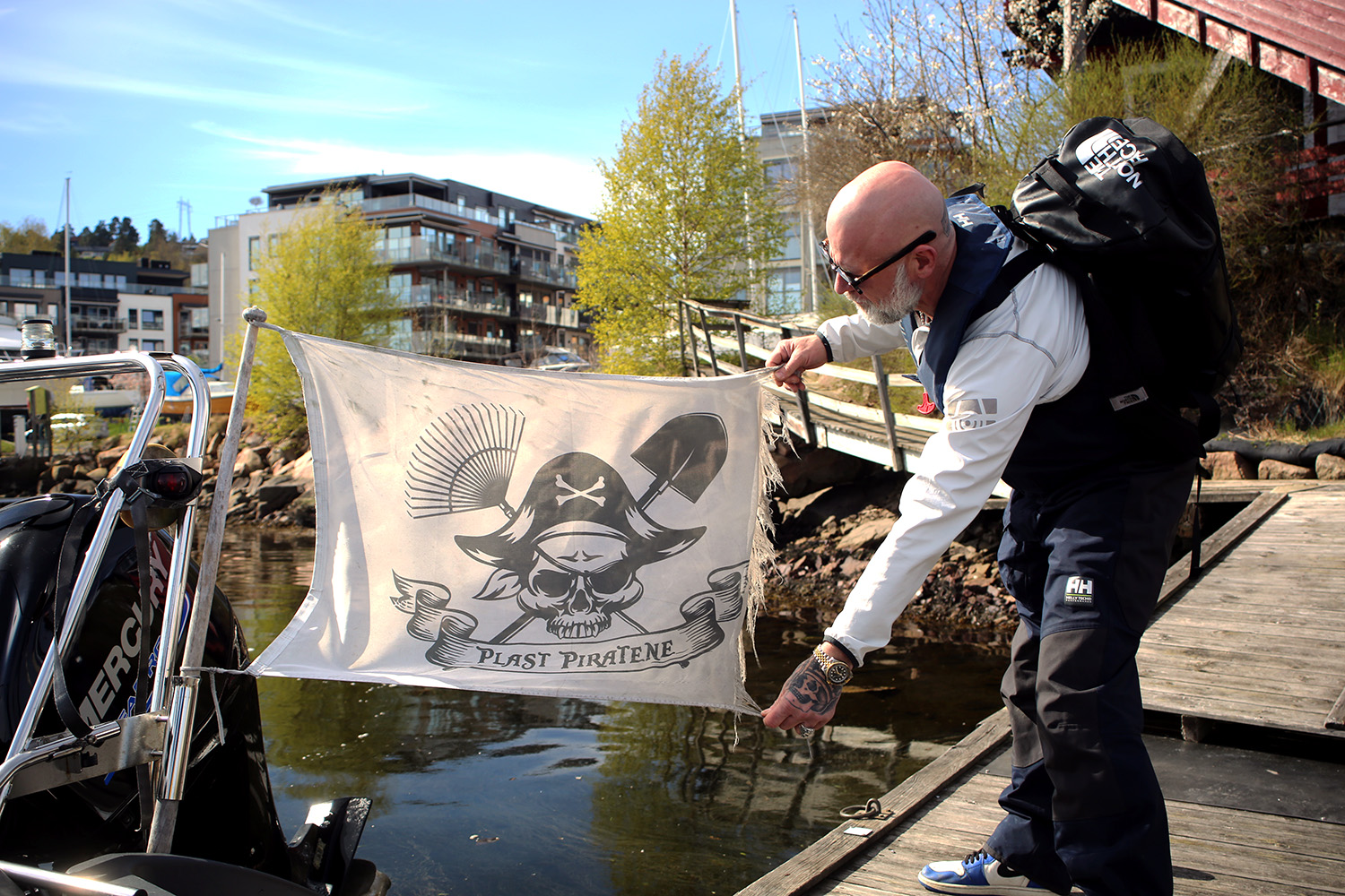David viser frem logoen til plastpiratene, som de har festet bak p&aring; b&aring;ten. 