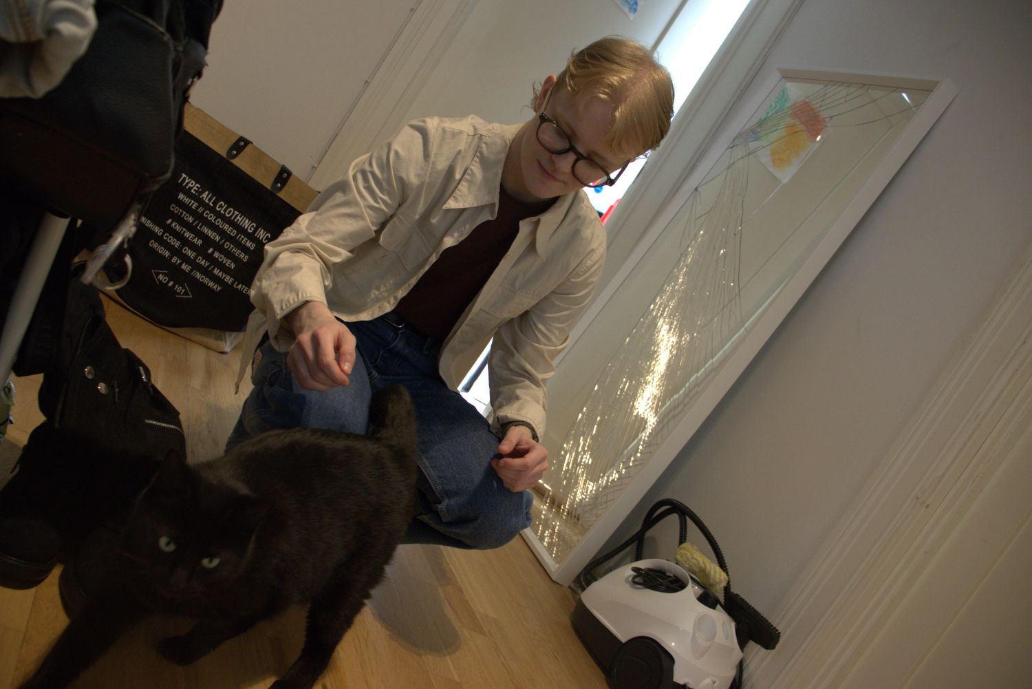 Mann klapper katt. I bakgrunnen knust speil