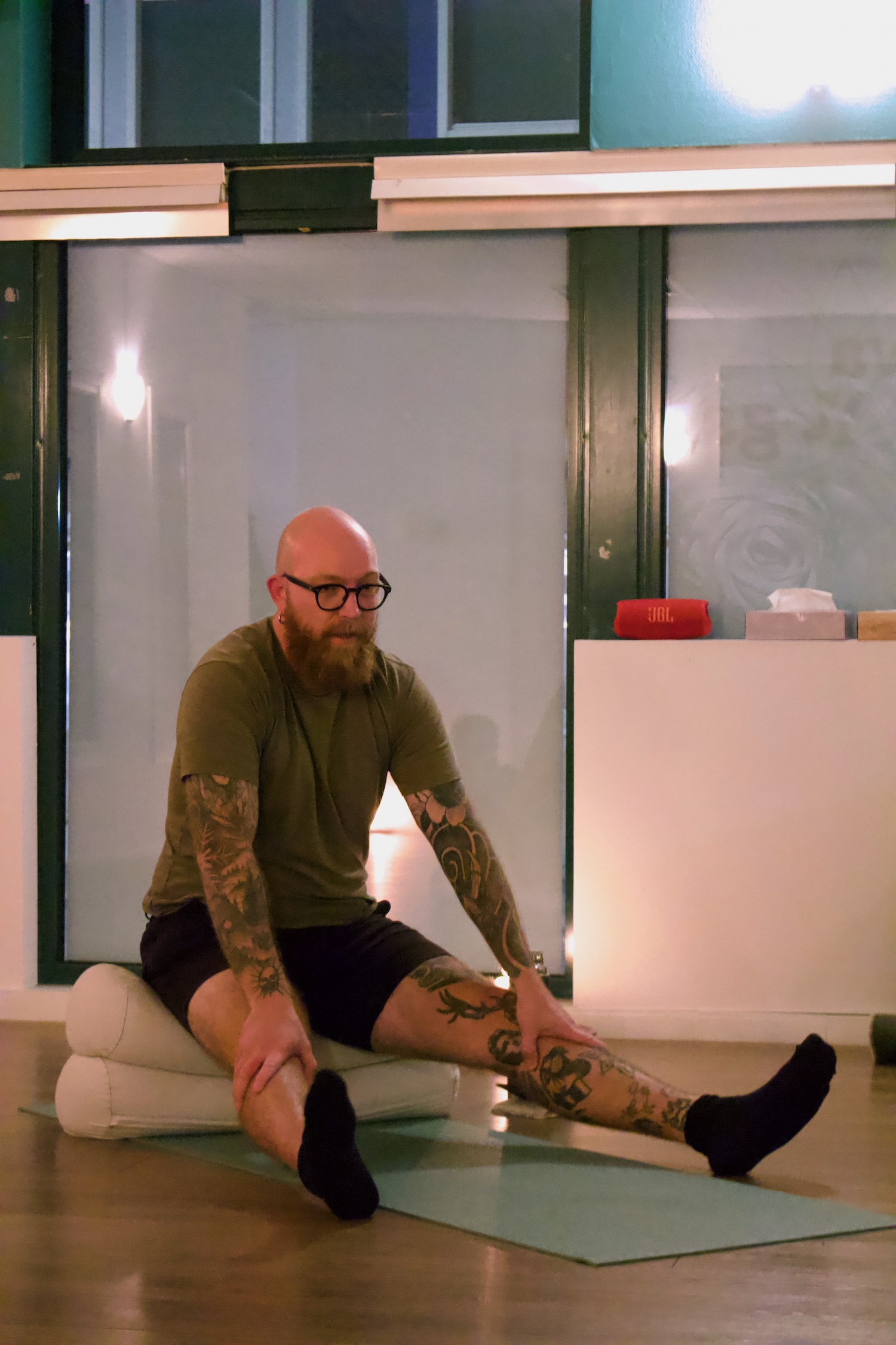 Skallet man sitter på yogamatte med strake bein