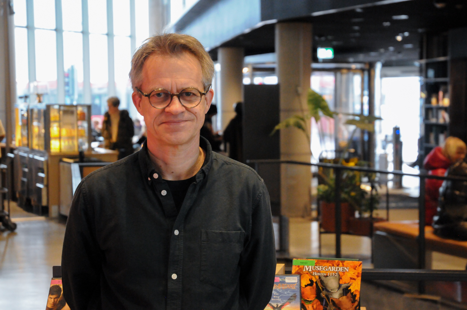 Mann står inne på biblioteket og smiler. 