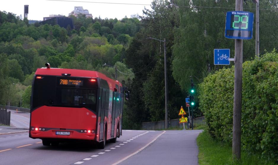 Fartsmåler og buss En buss kjører forbi en fartsmåler.
