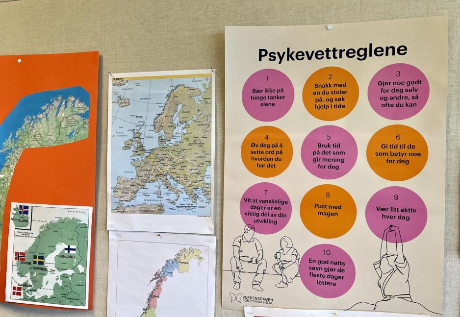 En vegg med flere plakater, blant annet norgeskart og en om Psykevettreglene.