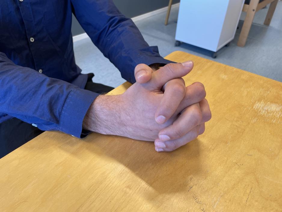 Den syriske storebroren på asylmottaket. To hender knyttet sammen på et bord.