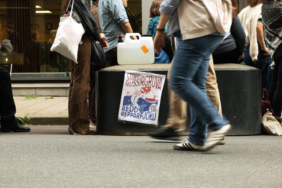 En plakat med Redd Repparfjord skrevet p&aring; den, i tillegg passerer folk forbi den.