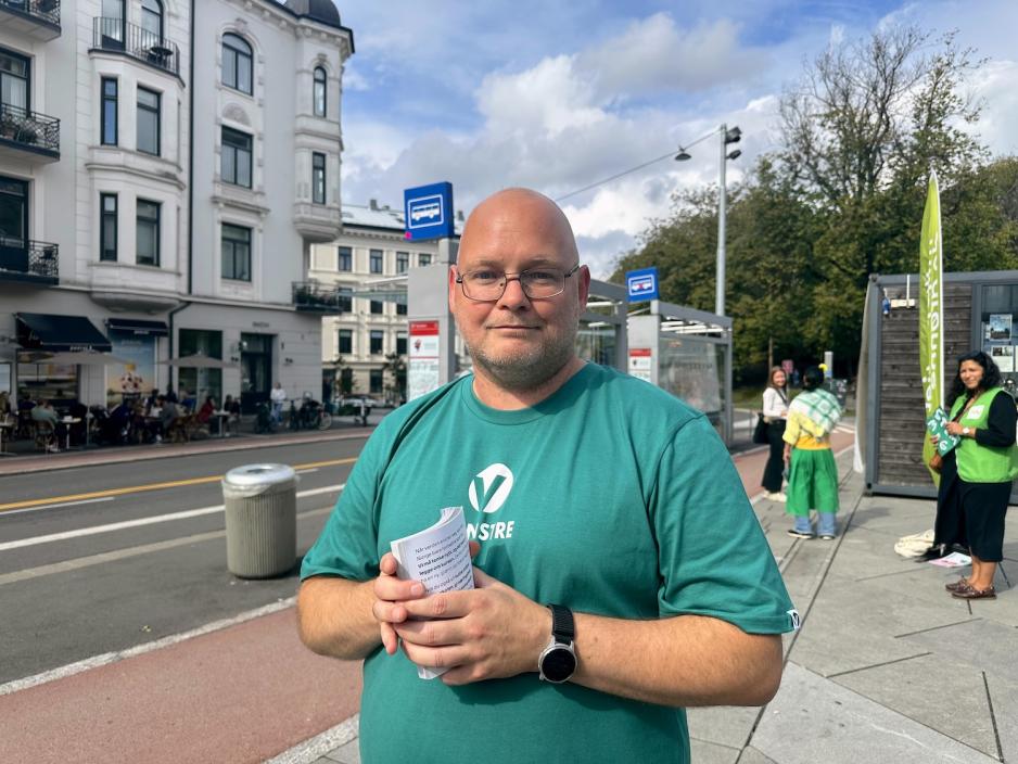 Stian Peeters står på St. Hanshaugen iført grønn Venstre-T-skjorte og briller. Han holder informasjonsark i hendene. I bakgrunnen snakker andre frivillige med forbipasserende.