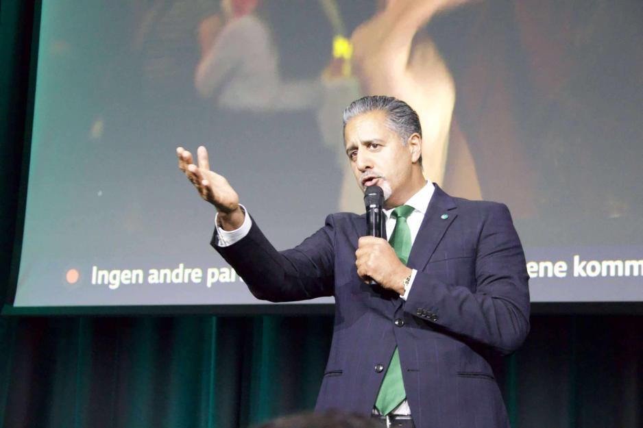 En mann i dress på scenen taler til publikum