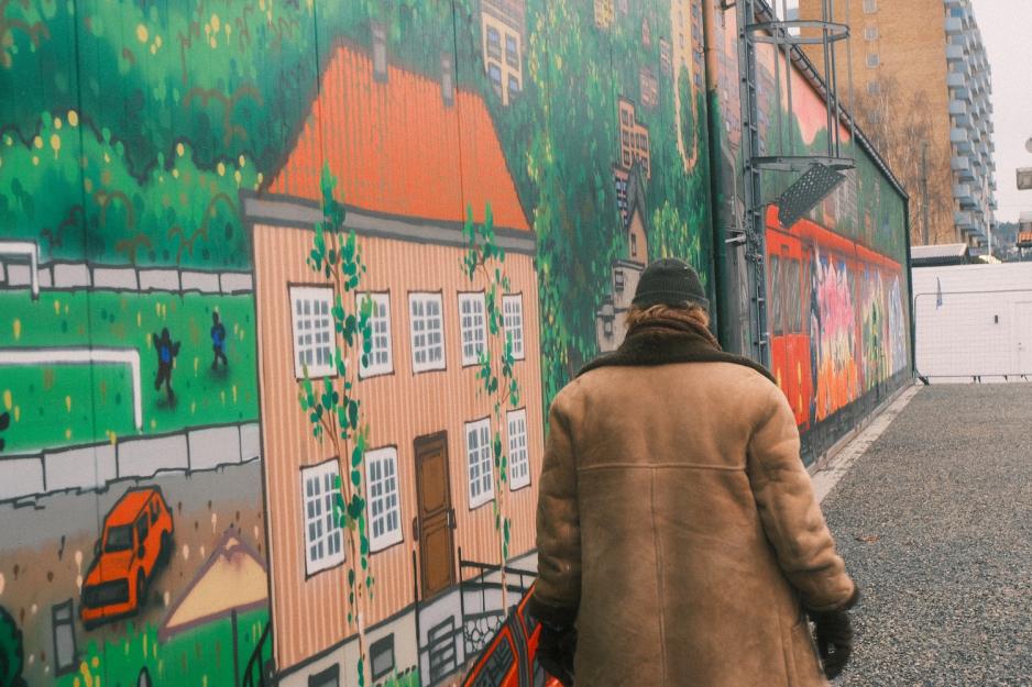 Mann gående foran et veggmaleri