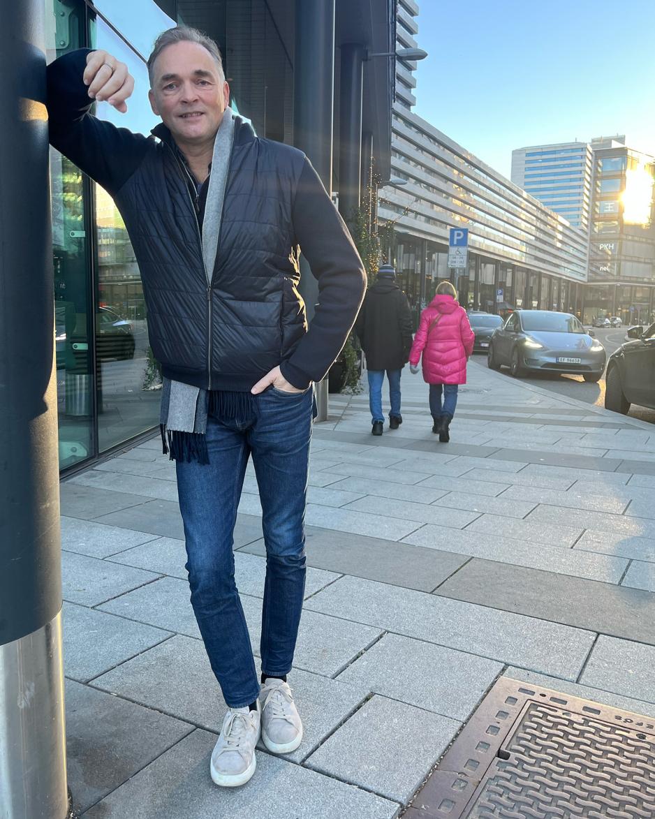 Fredrik Eckhoff lener seg på en stolpe i Karenlyst Allé og smiler