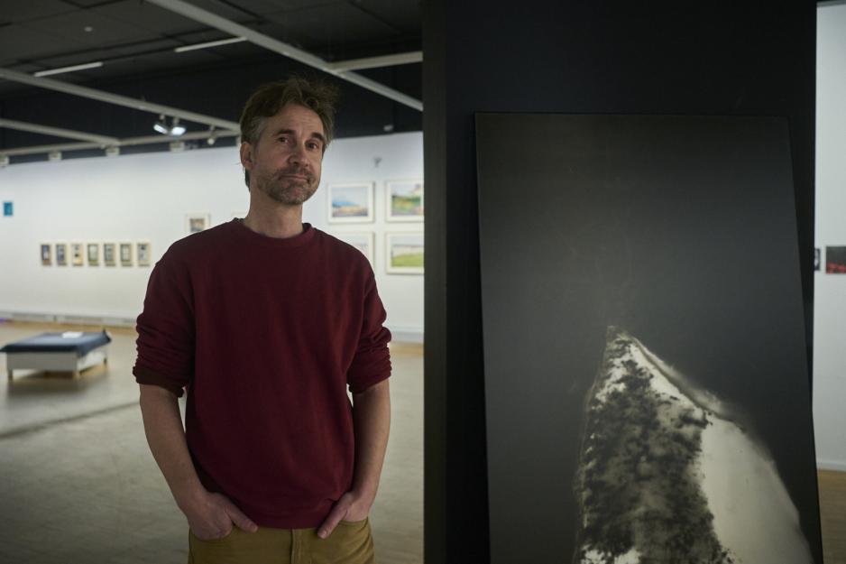 Fotograf Stig Marlon Weston ved siden av hans fotografier. 