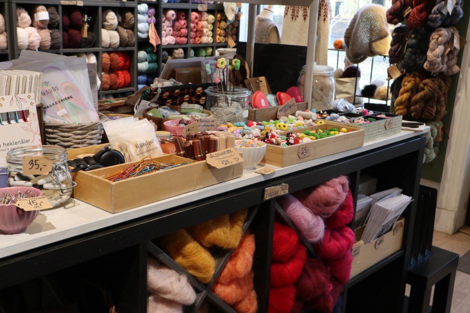 Et bord i en strikkebutikk med masse strikkeutstyr på.