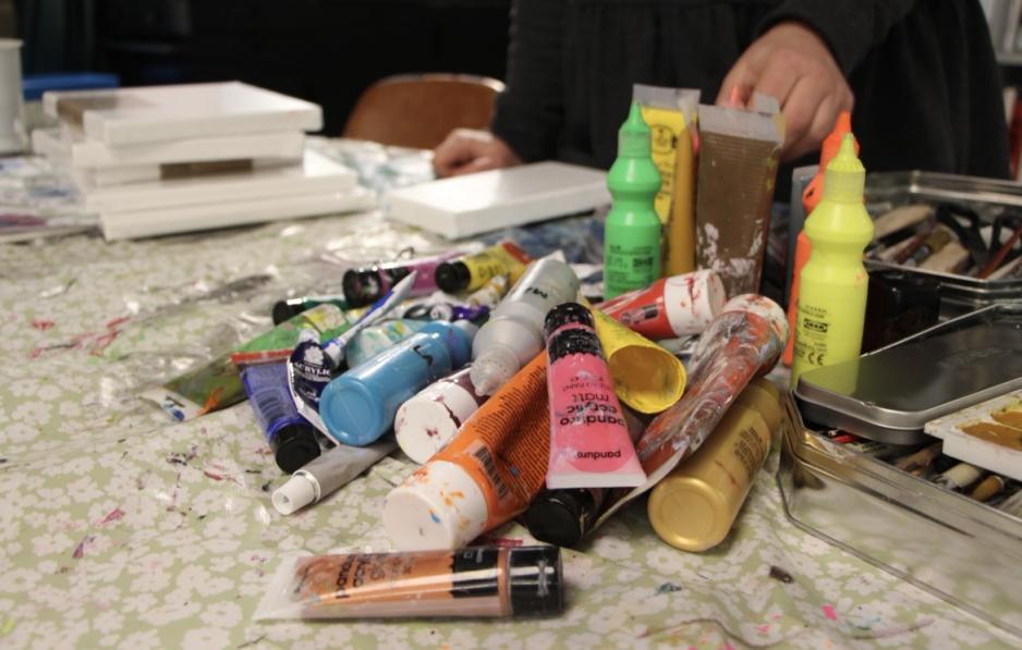 Maling og lerret ligger strødd på bordet 