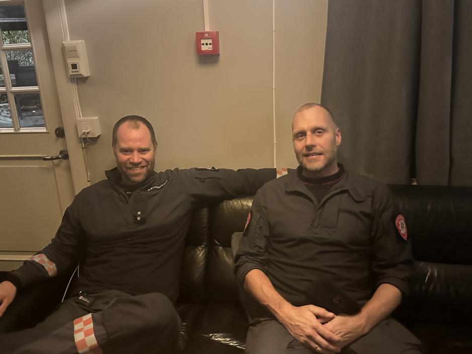 To brannmenn sitter og smiller til kameraet