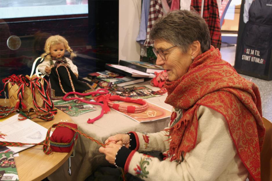 Medlem på Vestre Aker Husflidslag fletter hosebånd til bunad