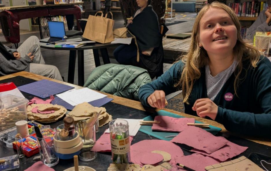 Celine Lyngås Sataøen sitter ved et bord på Deichman Stovner og lager papir