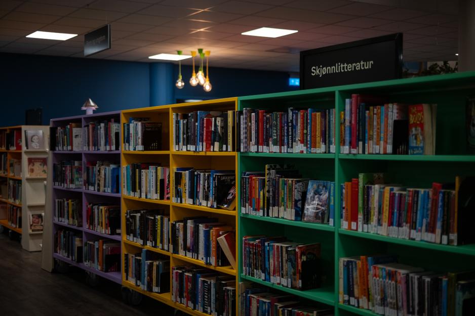 Biblioteks hyller fylt med bøker med et skilt som sier "Skjønnlitteratur"