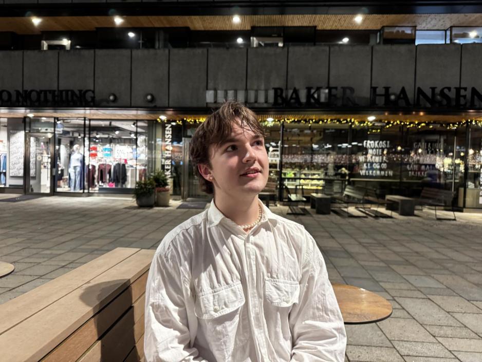 Ung mann sitter ute i byen p&aring; kvelden og ser opp