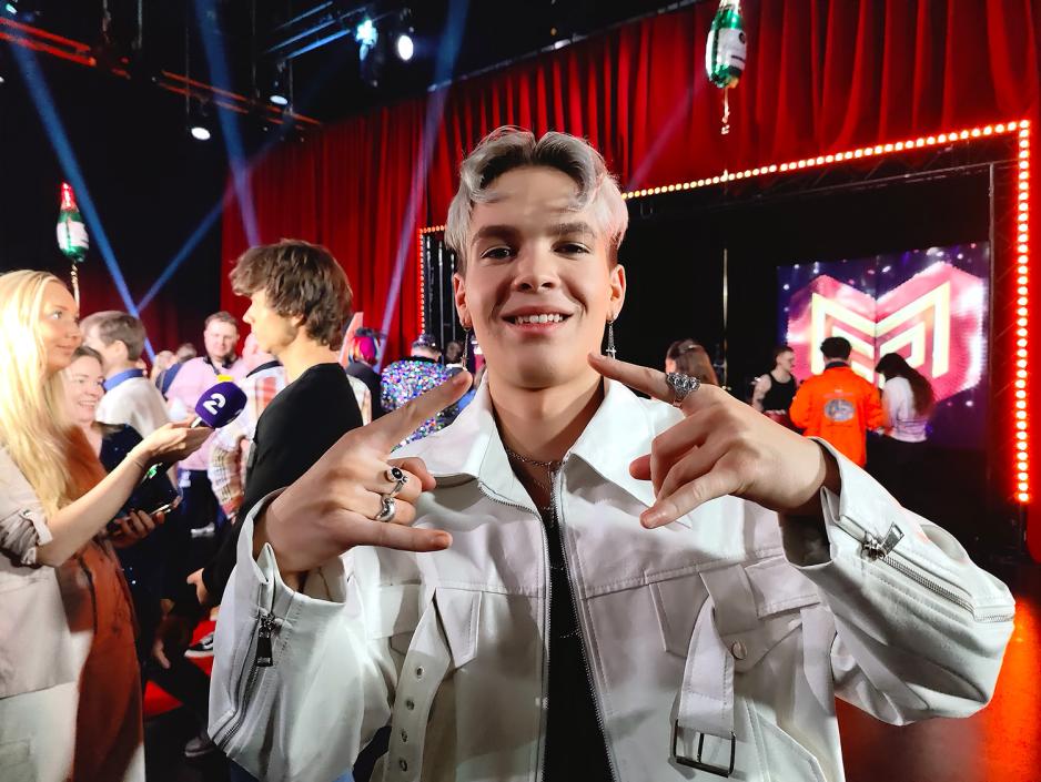 Gutt. Hvit jakke. Smiler. Lager tegn.