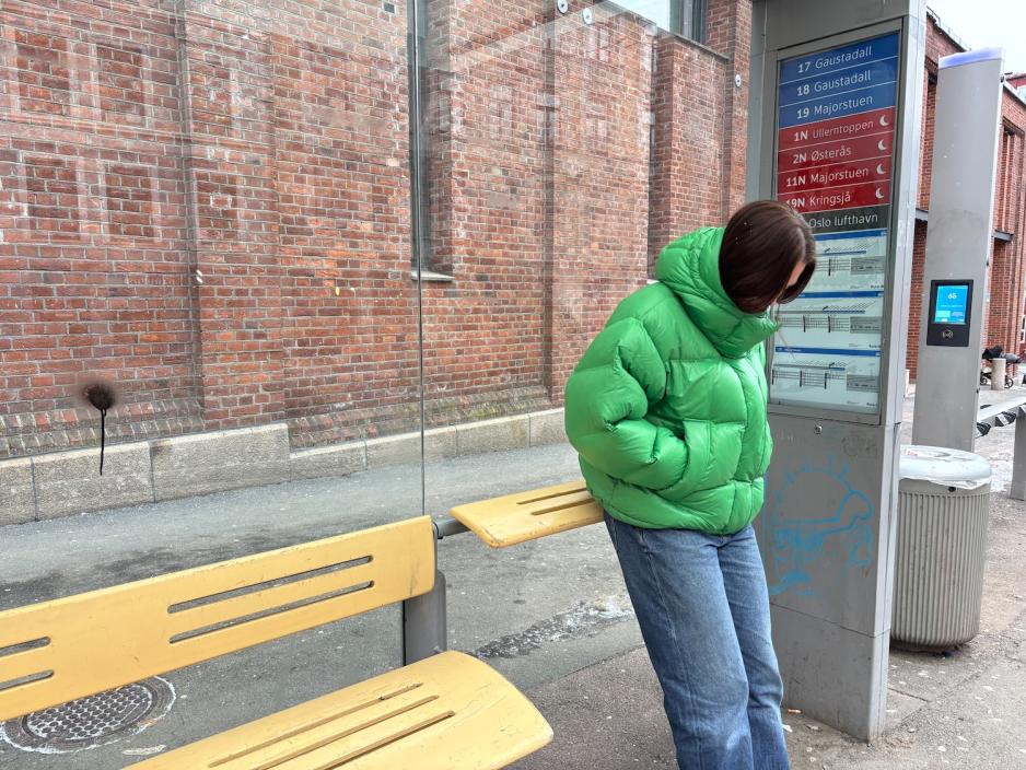 jente som lener seg p&aring; en skeiv benk p&aring; trikkestoppet Frydenlund i Oslo