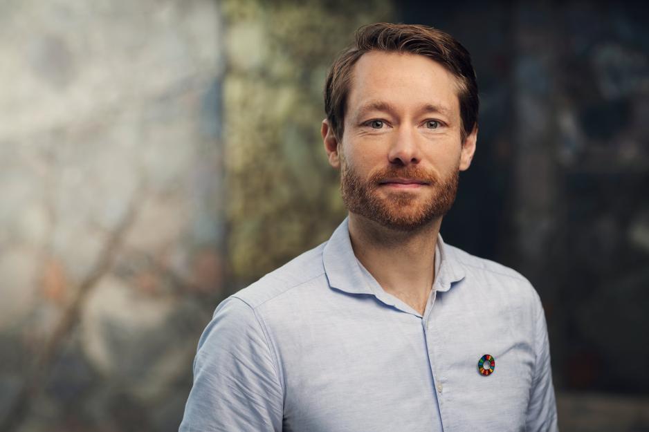 Mann st&aring;r i bl&aring; kjortet 