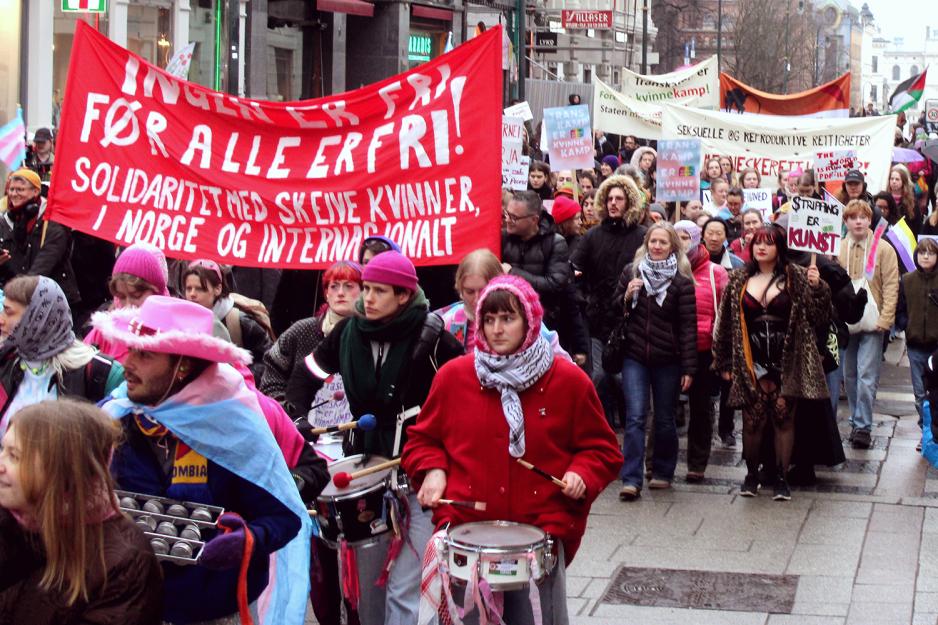 Toget for inkluderende 8. mars g&aring;r oppover Karl Johan. I bakgrunnen st&aring;r Alma Adore