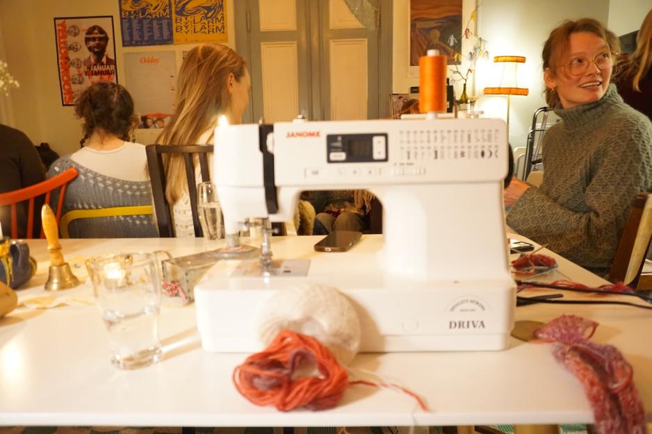 N&aelig;rbilde av symaskin med mennesker i bakgrunnen