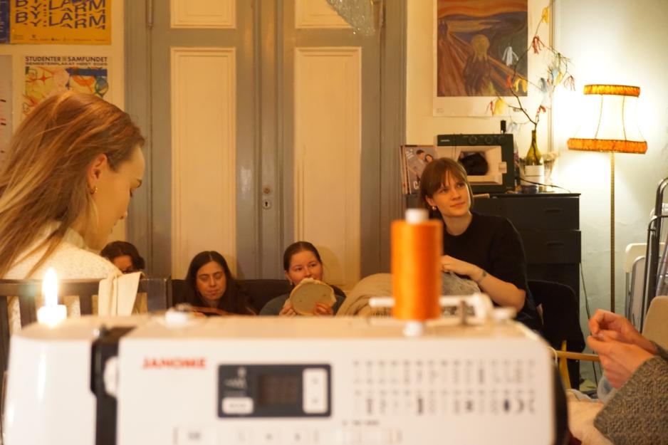 Bilde med fokus p&aring; mennesker i bakgrunnen og en symaskin som er foran uten fokus 