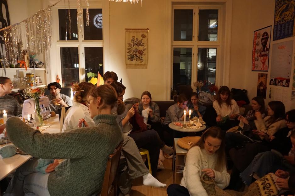 Full stue med mennesker som b&aring;de syr, strikker og snakker. 