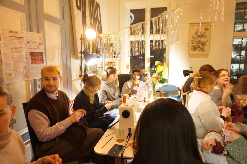 Mennesker som sitter rundt et bord p&aring; sykvelden hos husflidskollektivet