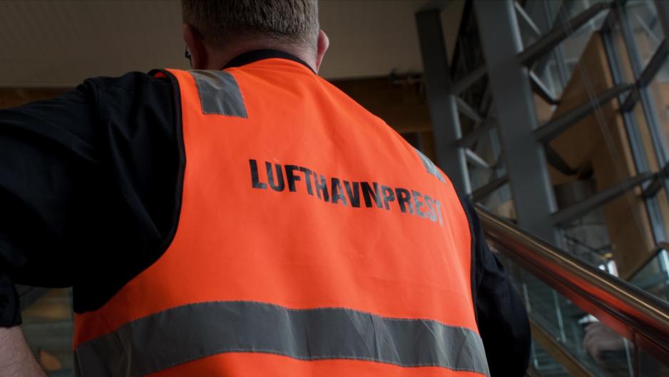 Refleksvest hvor det st&aring;r &laquo;lufthavnprest&raquo; p&aring; ryggen