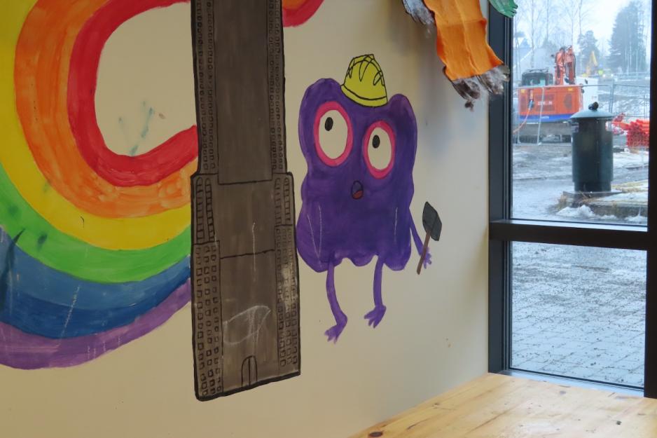 Figur malt p&aring; vegg under regnbue i en barnehage