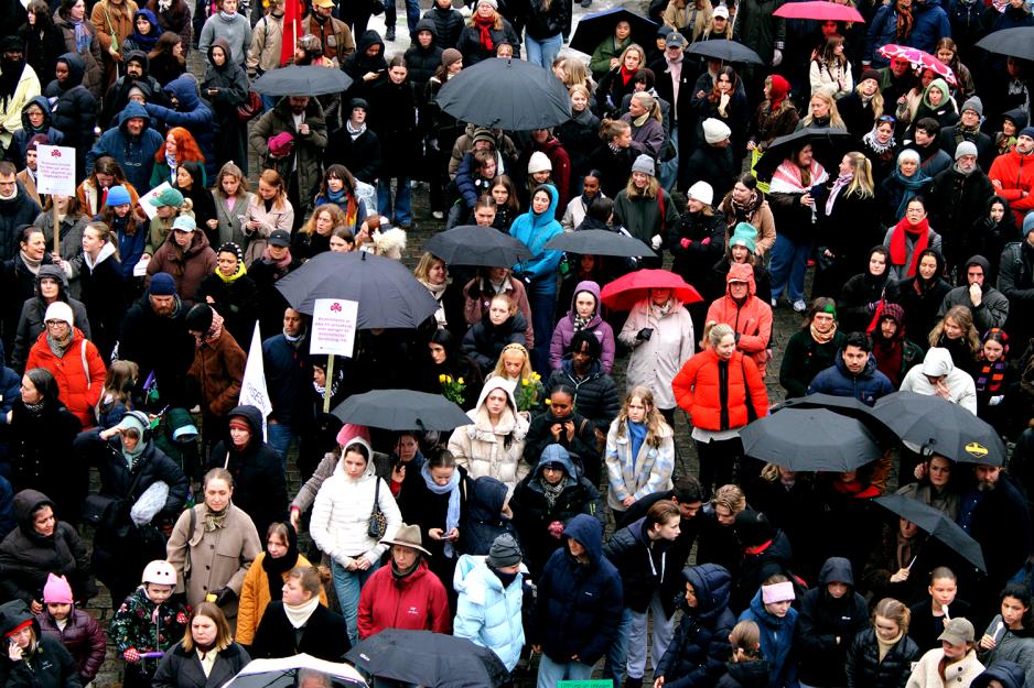 En folkemengde st&aring;r tett i tett. Midt i st&aring;r det tre ungdommer med gule roser for Tamima