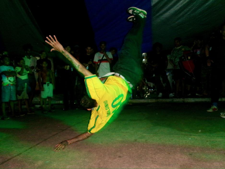En gutt danser hip-hop under rap-battle i favelaen. Han har p&aring; seg fotball t-skjorte.