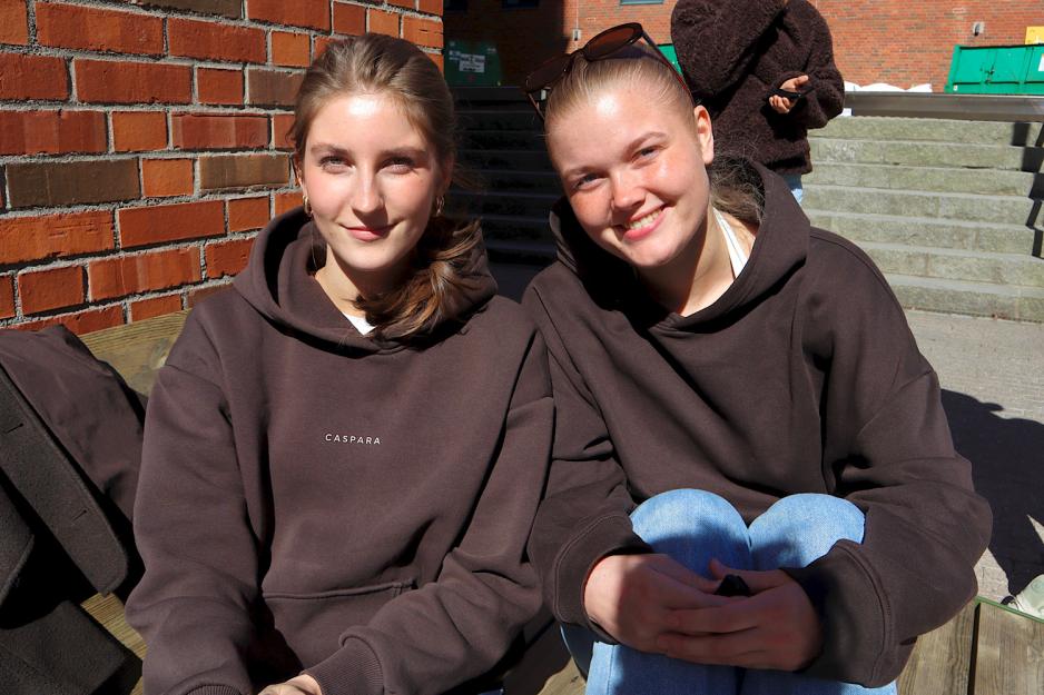 To jenter sitter sammen og smiler.