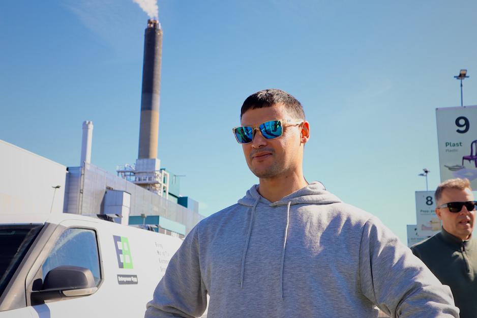 Mann st&aring;r med solbriller foran en gjenvinningsstasjon.