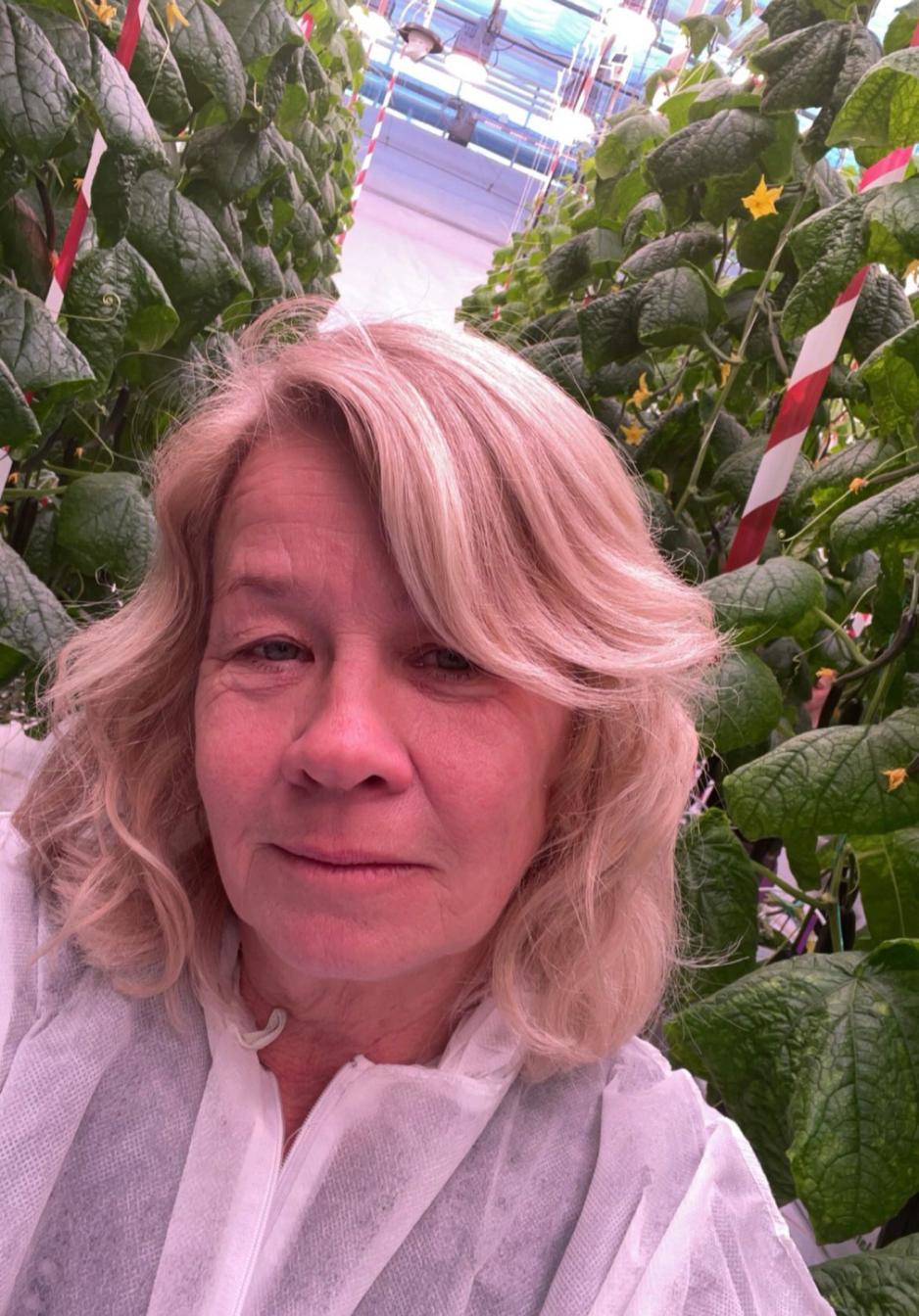 Sissel Torre st&aring;r i et veksthus med masse planter.