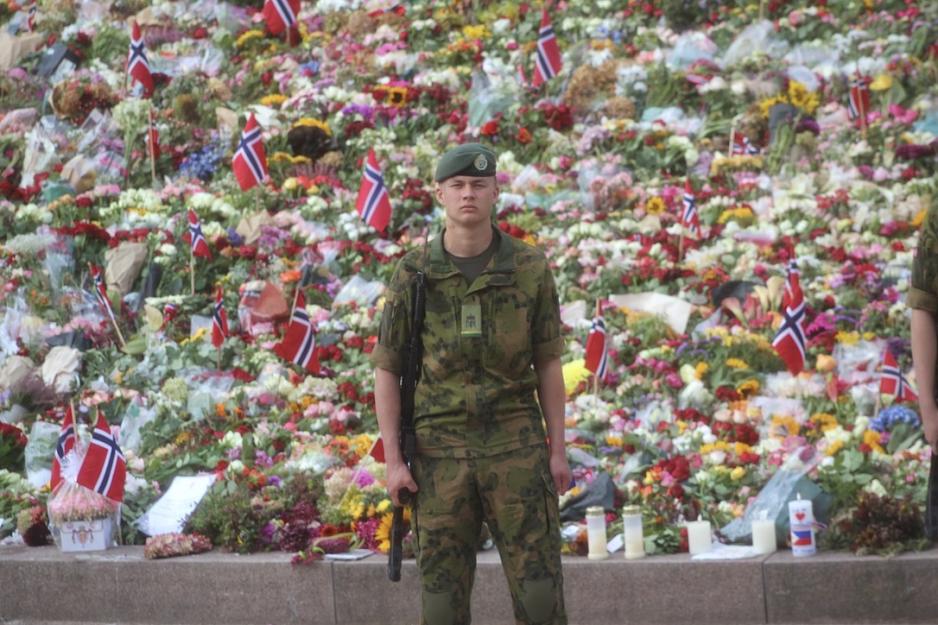 Soldat står foran blomsterhav.