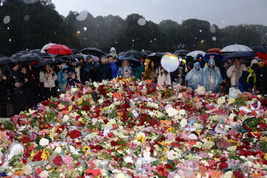 Publikum står i regn bak blomsterhavet foran Slottet