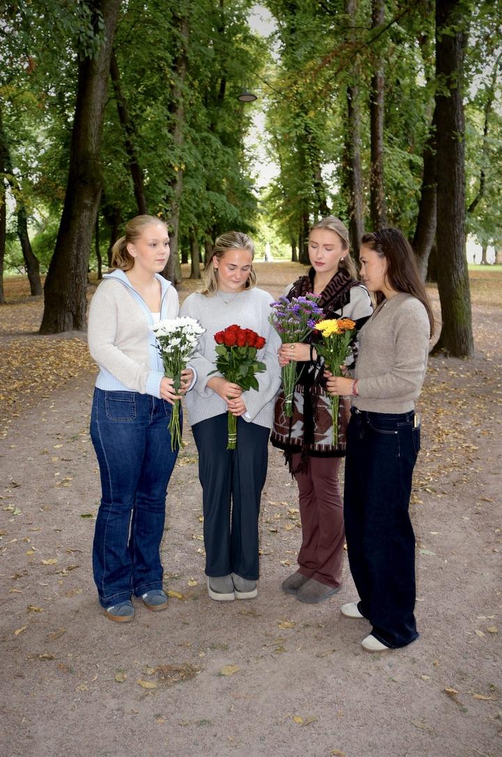 Tre unge kvinner står med hver sin bukett i hånden.